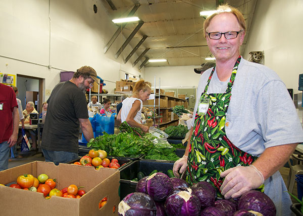 a man with red hair, glasses and a pepper apron stands by a pile of purple cabbage