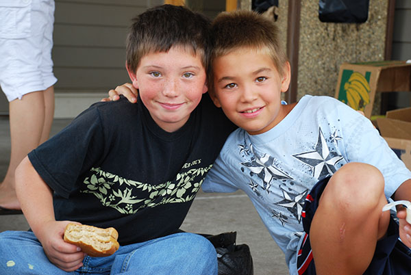 two boys sit together, with their arms around each other's shoulders