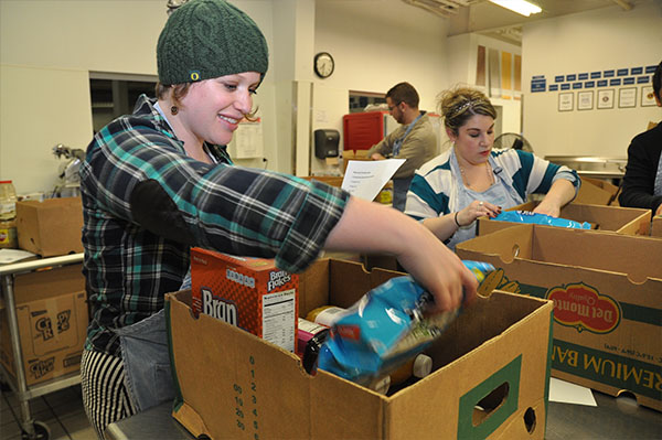 a young person sorts through food donations in a box